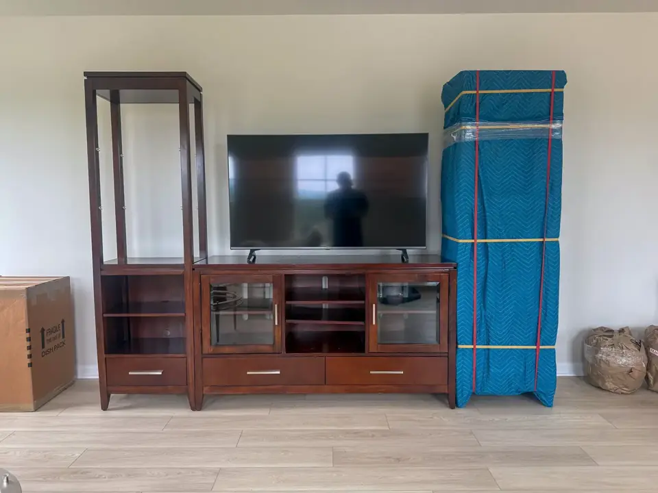 Television and wooden shelving, with one section protected by a blue moving pad