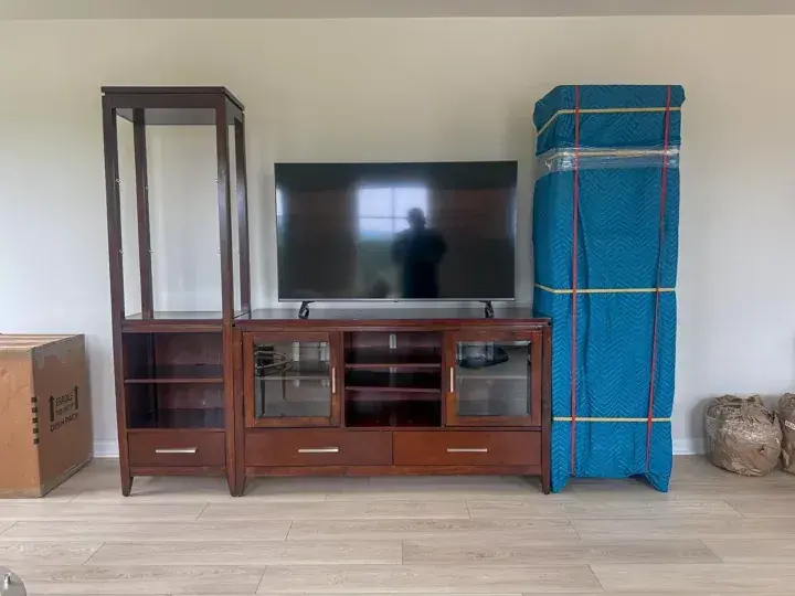 Television and wooden shelving, with one section protected by a blue moving pad