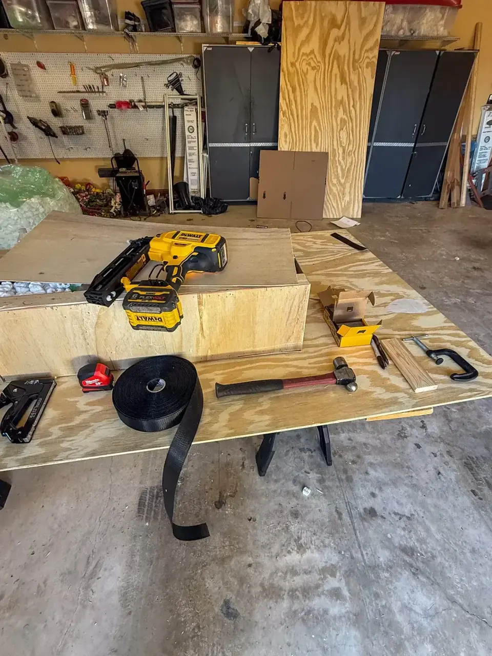 Wooden crate on a workbench with plywood, packing materials, and assembly tools