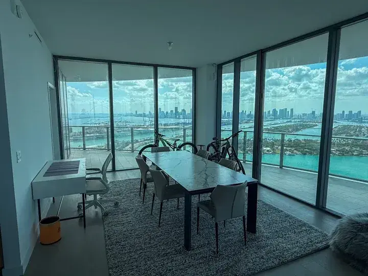 Dining table and chairs beside floor to ceiling windows