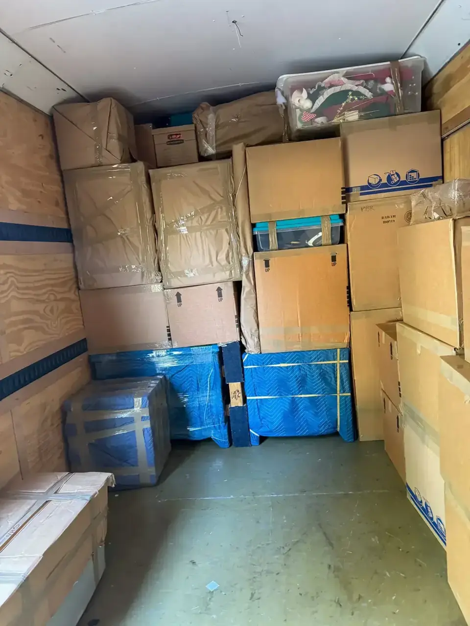 Cartons and padded furniture arranged inside a moving trailer