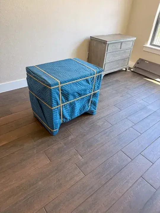 Dresser wrapped in blue moving pads and secured with bands