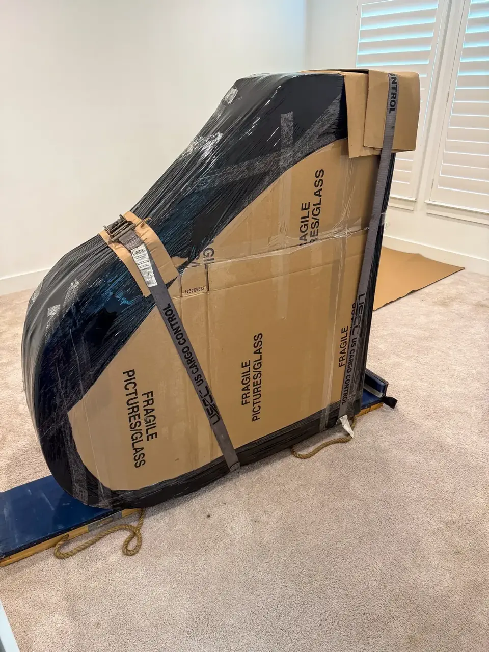 Baby grand piano wrapped and strapped on a padded piano board