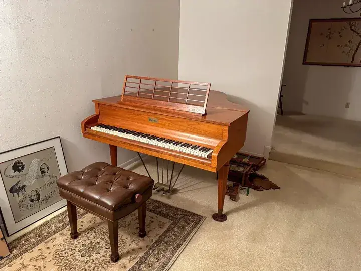 Wood finish upright piano and bench beside a doorway