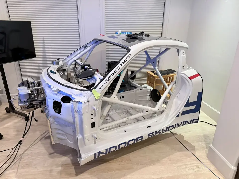 Car-body racing simulator with roll cage, controls, and connected components