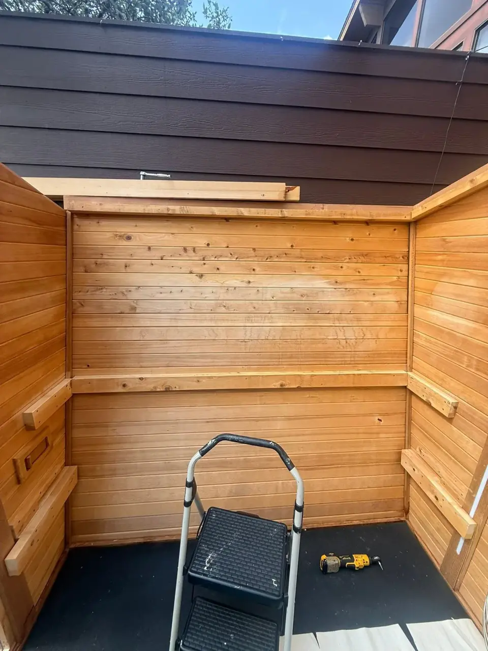 Wood-lined sauna cabin with a step ladder during preparation