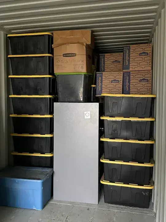 Cartons and lidded storage bins arranged inside a storage unit