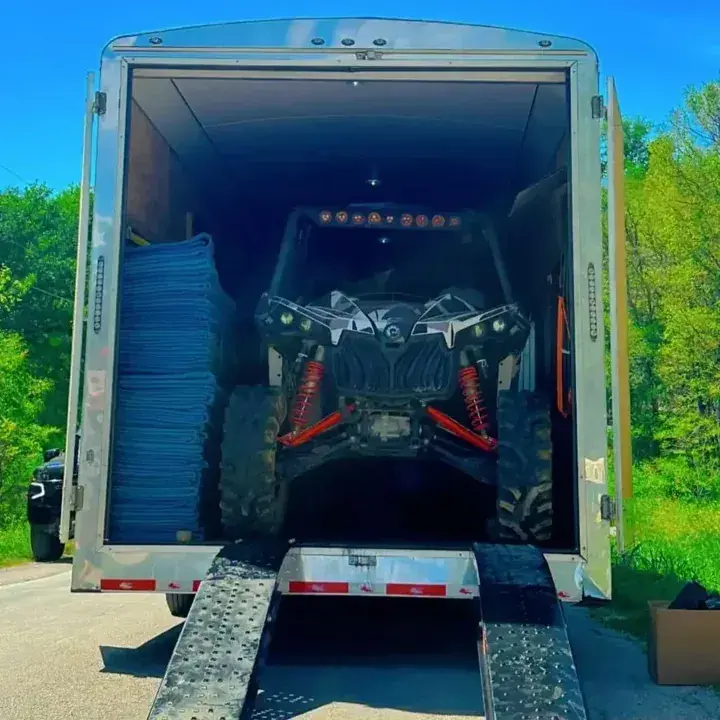 Open enclosed trailer with ramp and protected belongings inside