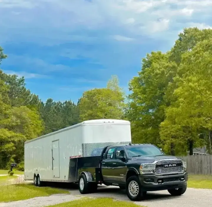 Pickup and enclosed moving trailer parked beside a tree lined road