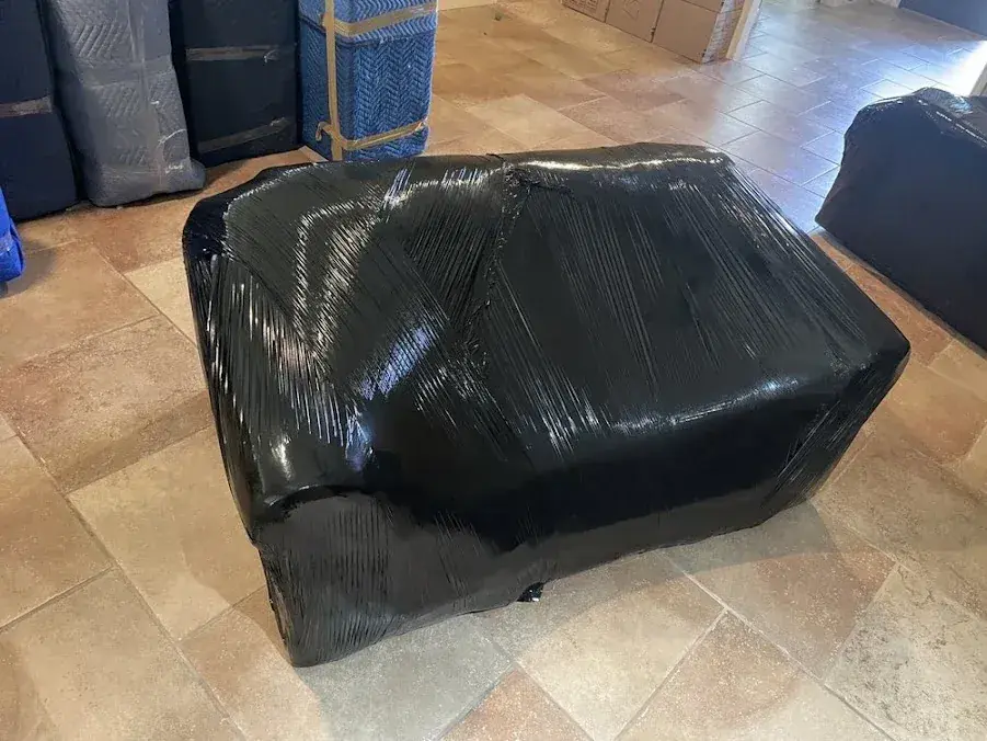 Sofa wrapped for moving with padded furniture behind it